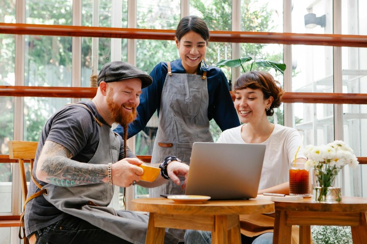Three people looking art one computer